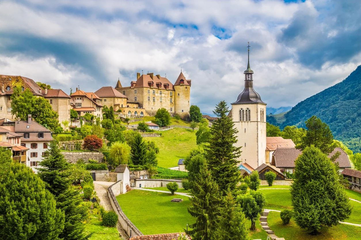 Castillo de Gruyères y pueblo medieval rodeados de montañas verdes